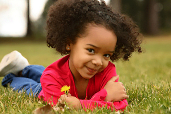 girl lying in the grass holding a flower